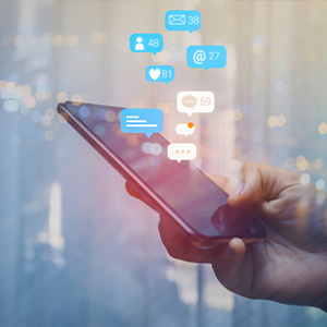 Hands holding a smartphone with floating social media icons and message bubbles.
