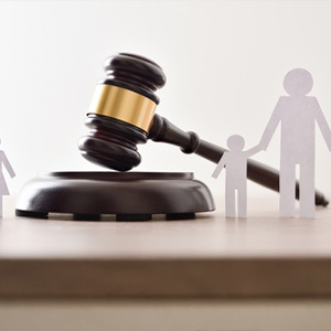 A legal gavel next to paper cutouts representing a family in a child custody case.