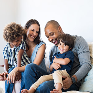 Happy family sitting on couch; New York child support modification legal help.